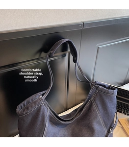 Détail du sac cabas en denim bleu foncé avec surpiqûres blanches et large bandoulière