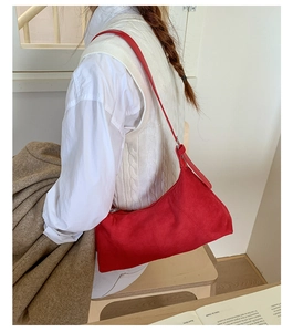Model wearing a red matte leather shoulder bag in a minimalist lifestyle setting