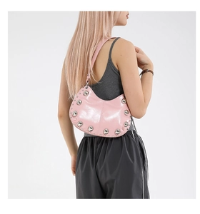 Détail du sac hobo rose brillant avec rivets argentés porté comme sac à bandoulière