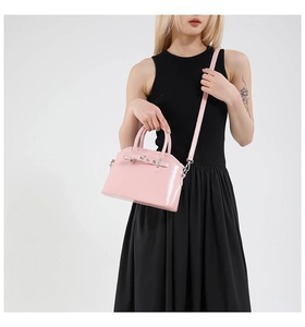 Detailed macro view of pink glossy patent leather texture and silver buckle on a tote bag
