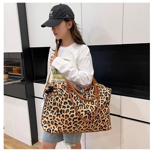 Close-up of large leopard print travel bag featuring brown leather straps and spacious design