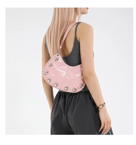 Detail of pink half-moon shoulder bag with silver metal studs shown on model