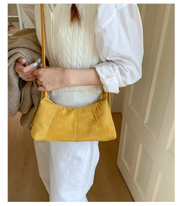 Close-up of bright yellow suede baguette bag with elegant vertical stitching details