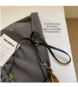 Detail of adjustable black leather strap and gold chain on quilted suede bag