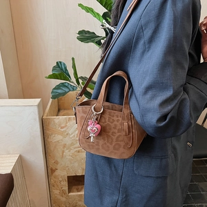 Dettaglio della mini borsa leopardata con ciondolo a cuore rosa e accessorio chiave