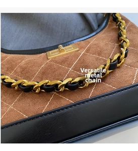 Detailed macro view of the brown suede material with diamond stitching and gold chain strap