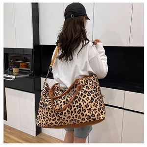 Leopard print travel bag with brown leather details shown on model in a modern kitchen