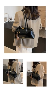 Detailed showcase of a black vintage glossy tote bag with gold hardware worn by a model.