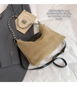 Detail of khaki suede tote bag with black leather flap and silver chain shoulder strap