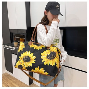 Large travel tote with sunflower print and leather straps worn by model in casual setting
