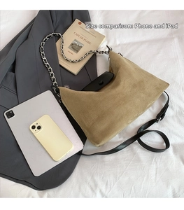 Detail of khaki suede hobo bag with black leather flap, silver chain and crossbody strap