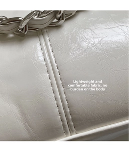 Detail of white patent leather with wrinkled texture and chunky silver metal chain