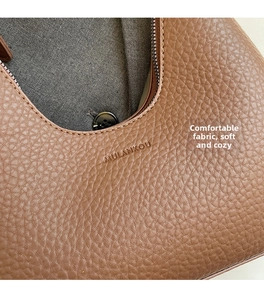 Close-up of brown litchi pattern leather texture and silver zipper of the shoulder bag
