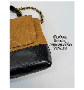 Detail showing the brown suede and black pebble leather stitching with gold chain