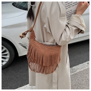 Close-up of brown suede hobo bag featuring double tassels and decorative wooden beads