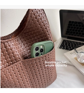 Détail d'un sac à bandoulière marron tressé montrant une poche latérale avec téléphone
