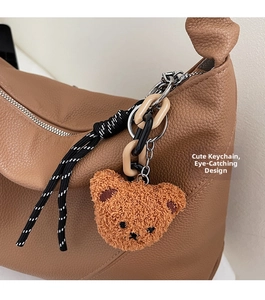 Détail d'une peluche d'ours avec chaîne sur un sac à main en cuir marron grainé