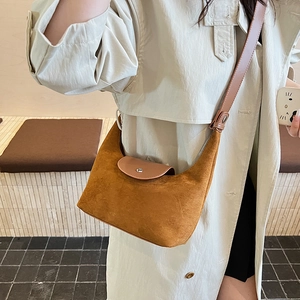 Detail of caramel suede hobo bag with dark leather flap and silver buckle closure