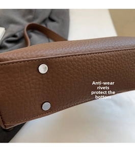 Detail of brown lychee leather bag bottom with silver protective metal studs