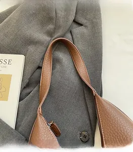 Detailed view of brown litchi grain leather shoulder bag with wide strap and silver zipper