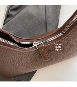 Macro shot of silver metal zipper and brown lychee grain leather texture on shoulder bag