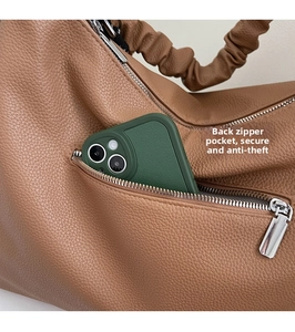 Détail de la poche zippée arrière d'un sac en cuir marron montrant le rangement antivol