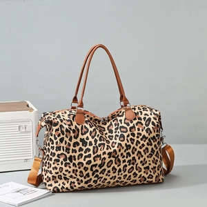 Detail of leopard print travel tote showing adjustable shoulder strap and leather handles