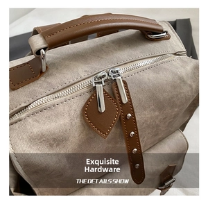 Detailed shot of durable dual metal zippers and leather pullers on grey canvas backpack