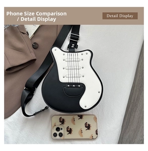 Detail view of guitar shaped crossbody bag with studs beside a phone for size comparison