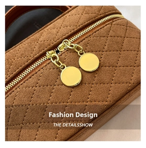 Detailed macro view of the gold double-zipper and brown quilted suede texture on the bag