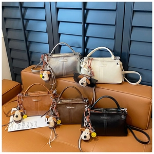 Detailweergave van vijf kleurrijke leren crossbodytassen met schattige puppy-hangers eraan