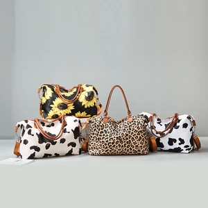 Detail view of stylish leopard and floral print duffle bags with premium leather handles