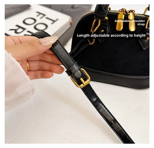 Détail de la bandoulière en cuir réglable avec boucle dorée sur un sac à main coquillage