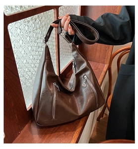 Detail of dark brown hobo tote bag featuring dual vertical zippers and soft leather texture