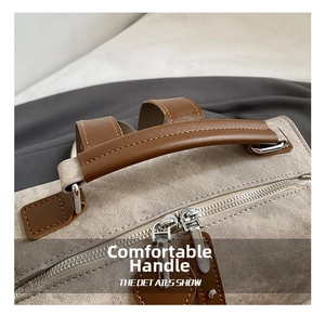 Close-up of canvas backpack showing brown leather handle and dual metal zippers