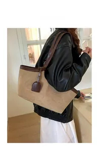 Detail view of khaki suede tote bag with brown leather handles worn by a model