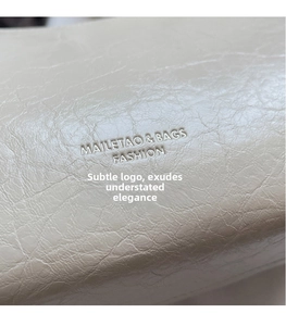 Detail of cream textured leather bag featuring an embossed Mailetao fashion logo
