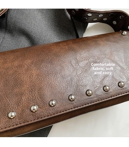 Détail du sac en cuir marron vintage avec garniture de clous métalliques et doublure douce