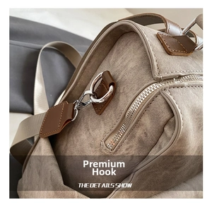 Detail showing the durable silver metal hooks and brown leather trim on a khaki backpack