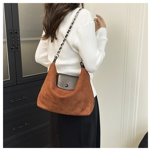 Detail of caramel suede hobo bag with black leather flap and silver chain shoulder strap