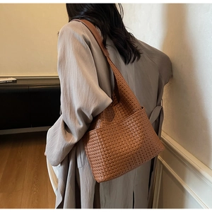 Vue détaillée du sac hobo en cuir tressé marron caramel porté par un mannequin chic