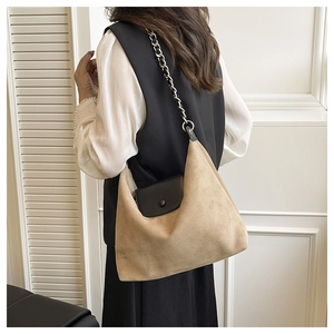 Detail view of suede tote bag with thick silver chain strap worn by a model