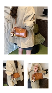 Detail van vintage bruine PU-lederen tas met puppy-hanger en stijlvol gestreept lint