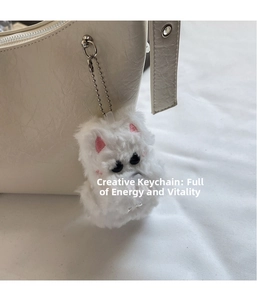 White fluffy puppy keychain charm on a beige pebbled leather shoulder handbag
