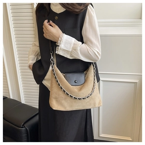 Detail of khaki suede tote bag featuring black leather flap and woven chain strap