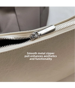 Macro shot of ivory leather texture and smooth silver metal zipper on the bag