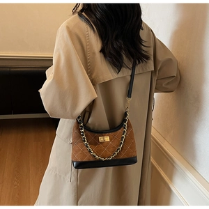 Detail of brown quilted suede shoulder bag featuring a gold twist lock and chain strap
