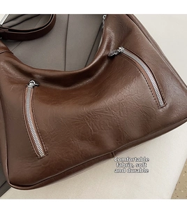 Detailed view of the dark brown matte leather bag featuring double diagonal zipper pockets