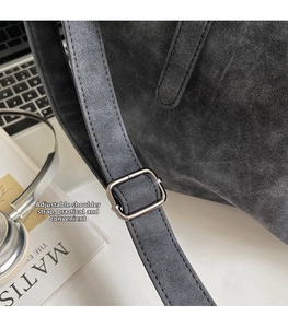Detail of adjustable shoulder strap and silver metal buckle on gray matte tote bag