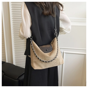 Detail of khaki suede tote bag with black leather flap and woven chain shoulder strap
